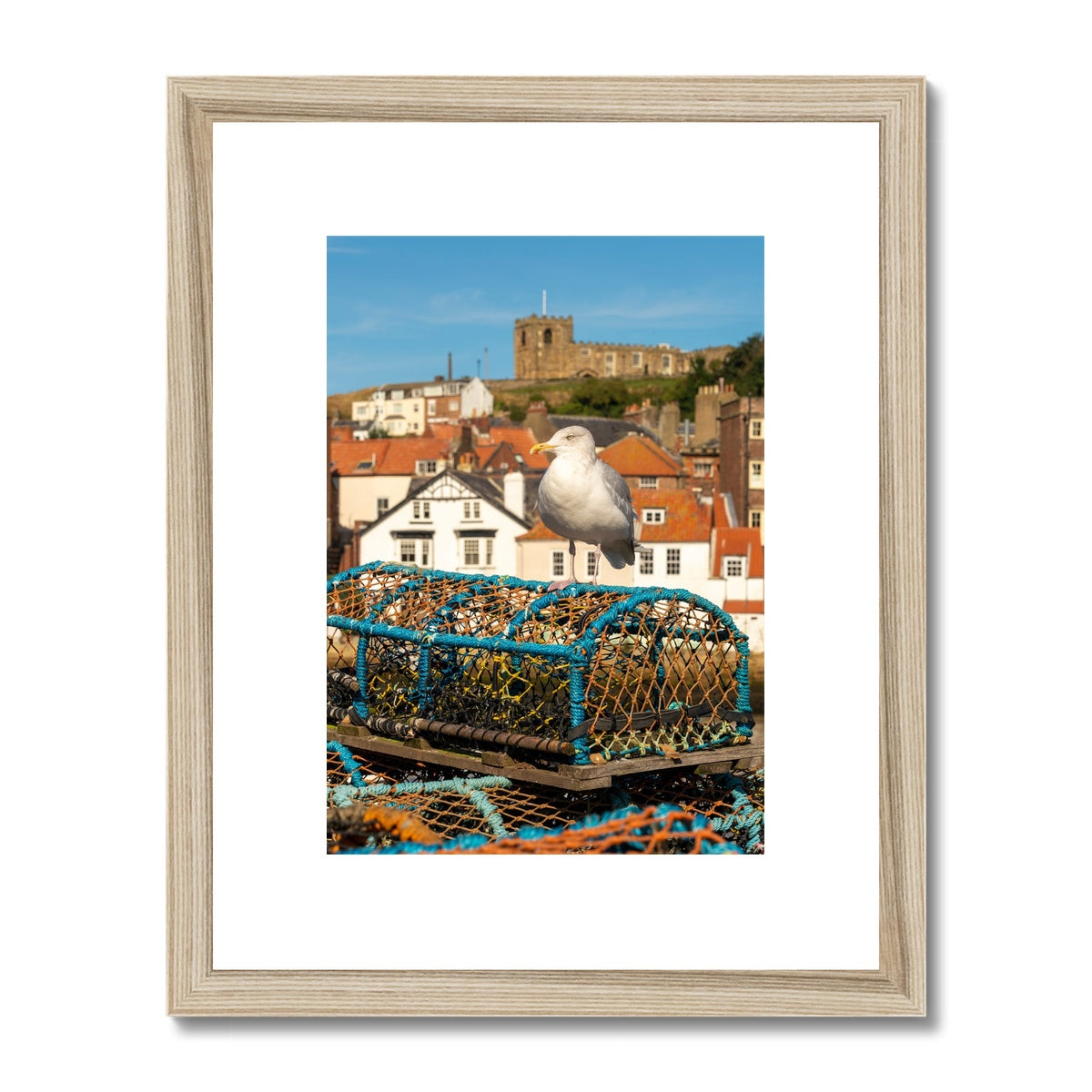 Seagull standing on a lobster trap on the quayside of Whitby harbour with St Mary's church in the distance. Whitby, UK. Framed & Mounted Print