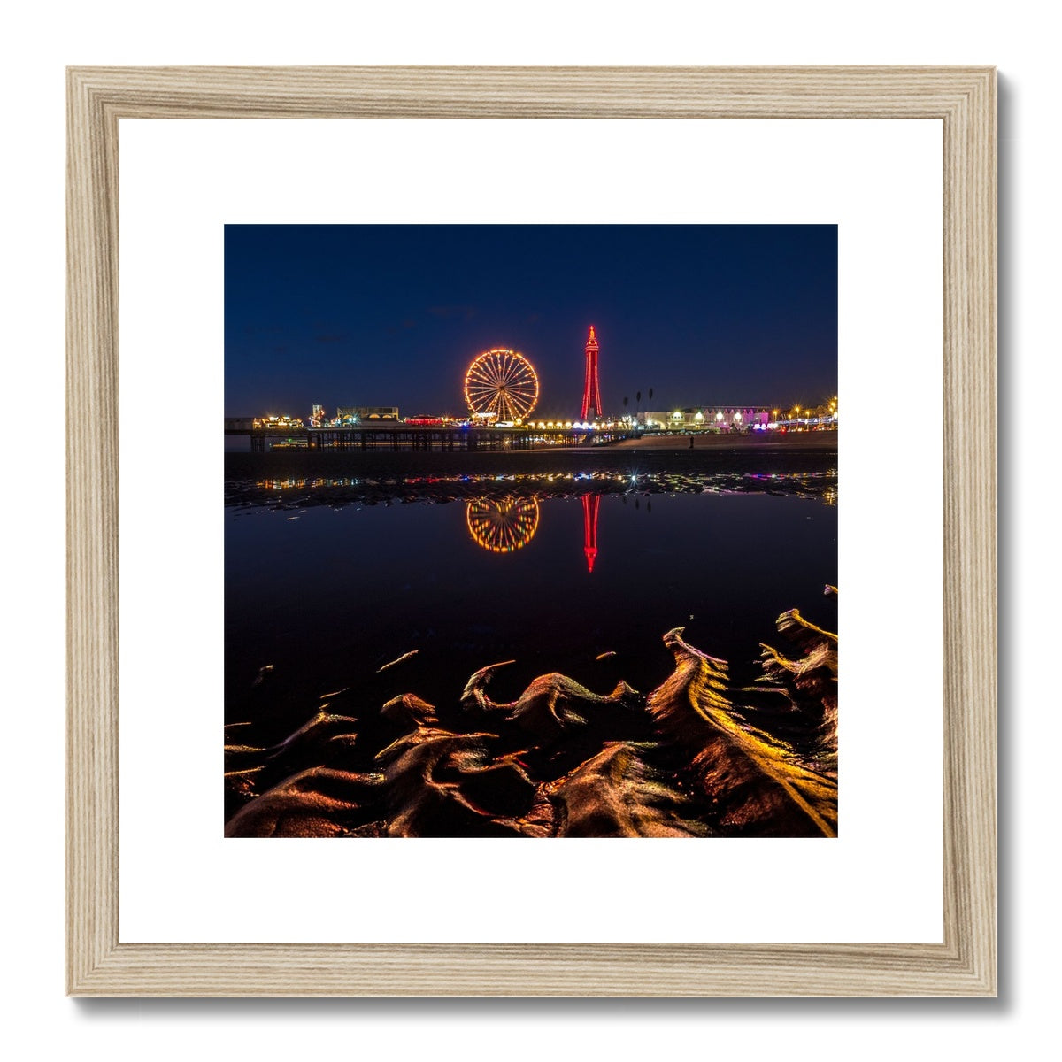Blackpool Tower and Central Pier at night, with reflection of illuminations in water on the beach  UK. Framed & Mounted Print