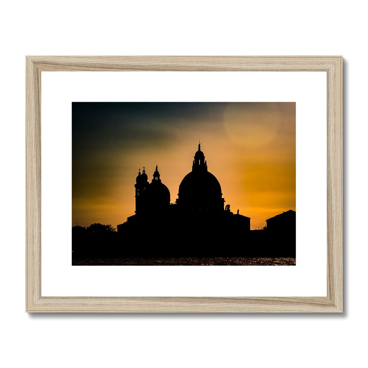 Silhouette of Santa Maria della Salute on the Grand Canal in Venice against a golden sky at sunset. Italy. Framed & Mounted Print