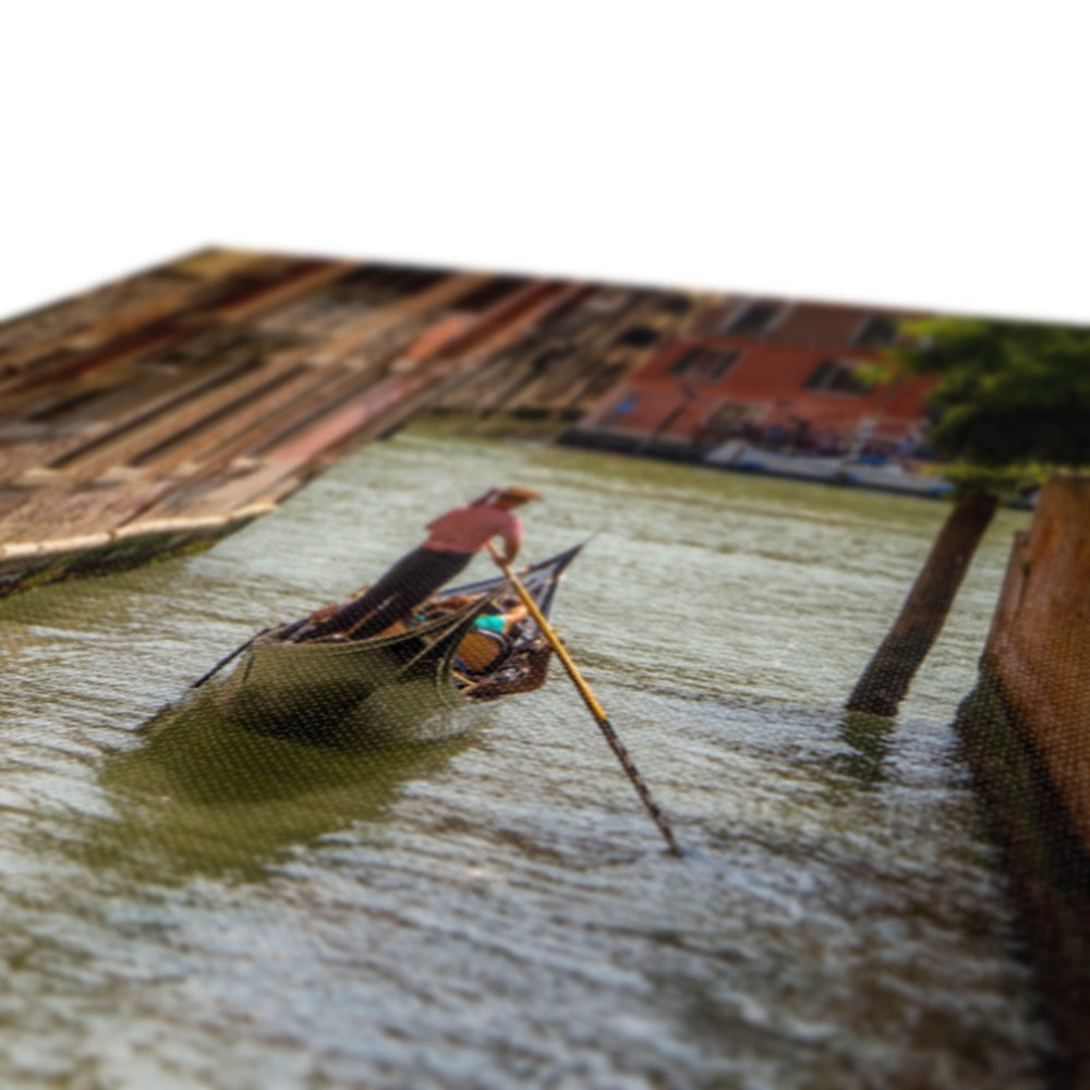 Gondola with gondolier wearing a traditional boater hat and striped top on a  canal in Venice. Italy. Canvas