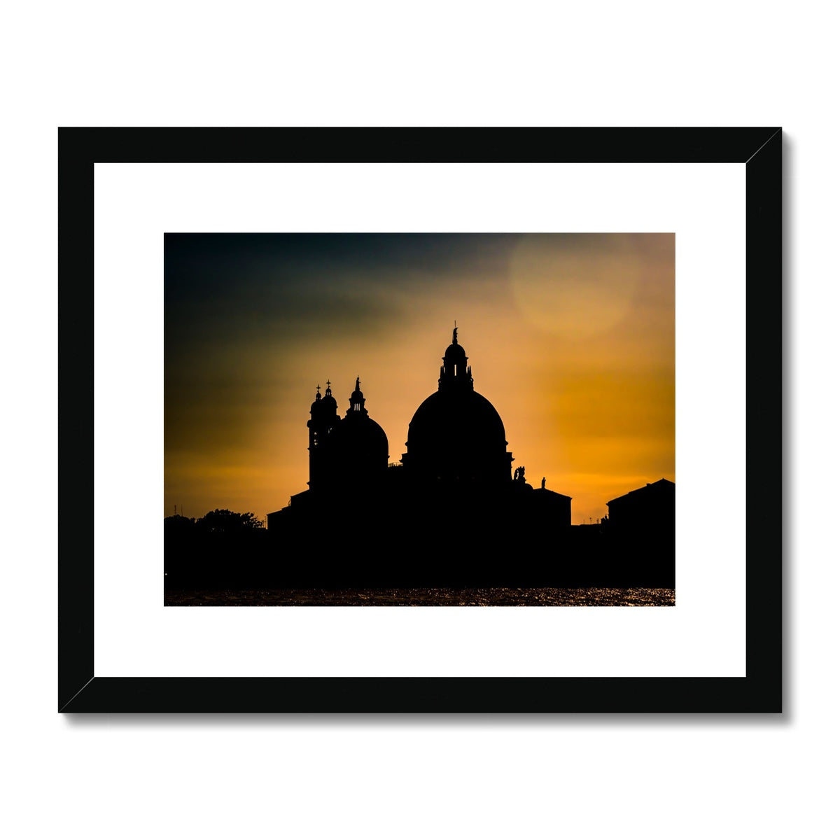 Silhouette of Santa Maria della Salute on the Grand Canal in Venice against a golden sky at sunset. Italy. Framed & Mounted Print