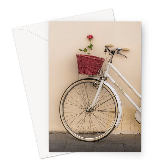 White bicycle parked against a  rendered wall with a red rose in its basket, Rome, Italy. Greeting Card