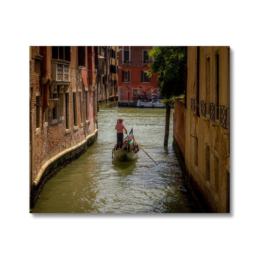 Gondola with gondolier wearing a traditional boater hat and striped top on a  canal in Venice. Italy. Canvas