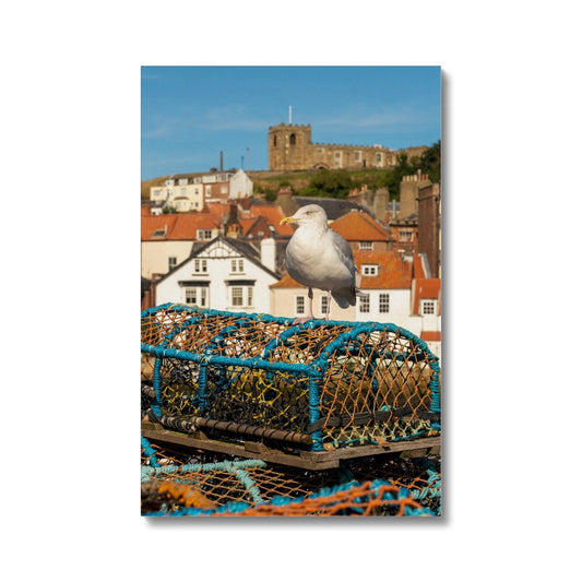 Seagull standing on a lobster trap on the quayside of Whitby harbour with St Mary's church in the distance. Whitby, UK. Canvas