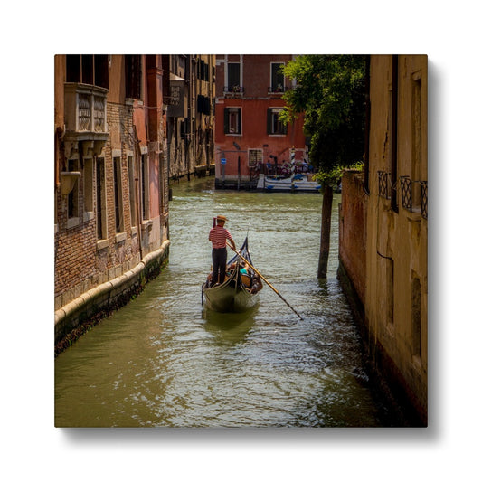 Gondola with gondolier wearing a traditional boater hat and striped top on a  canal in Venice. Italy. Canvas