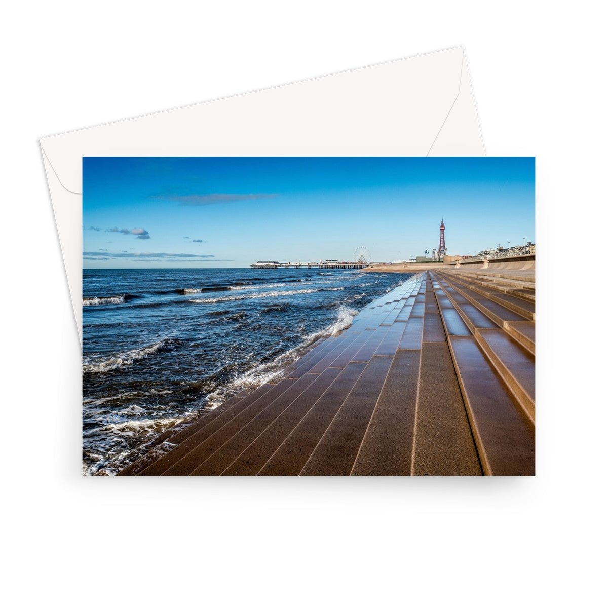 Blackpool's stone stepped sea defences with Blackpool Tower and Central Pier in the distance, Blackpool, UK. Greeting Card