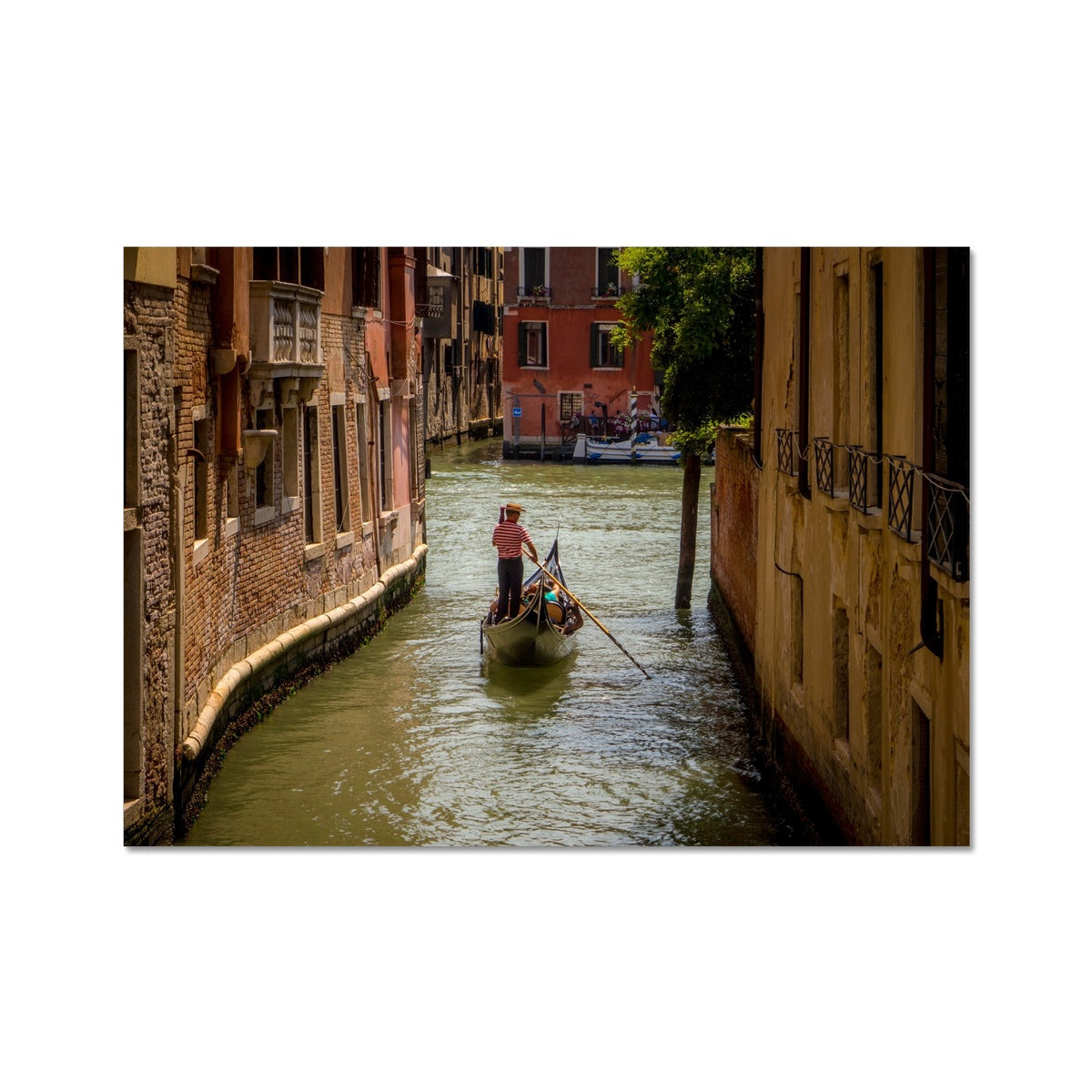 Gondola with gondolier wearing a traditional boater hat and striped top on a  canal in Venice. Italy. Fine Art Print