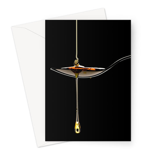 Honey pouring on to metal spoon and dripping off against black background. Greeting Card