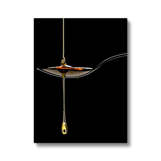 Honey pouring on to metal spoon and dripping off against black background. Canvas