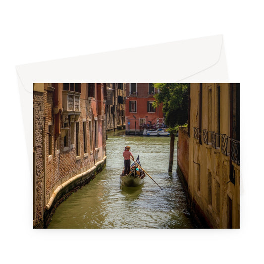 Gondola with gondolier wearing a traditional boater hat and striped top on a  canal in Venice. Italy. Greeting Card
