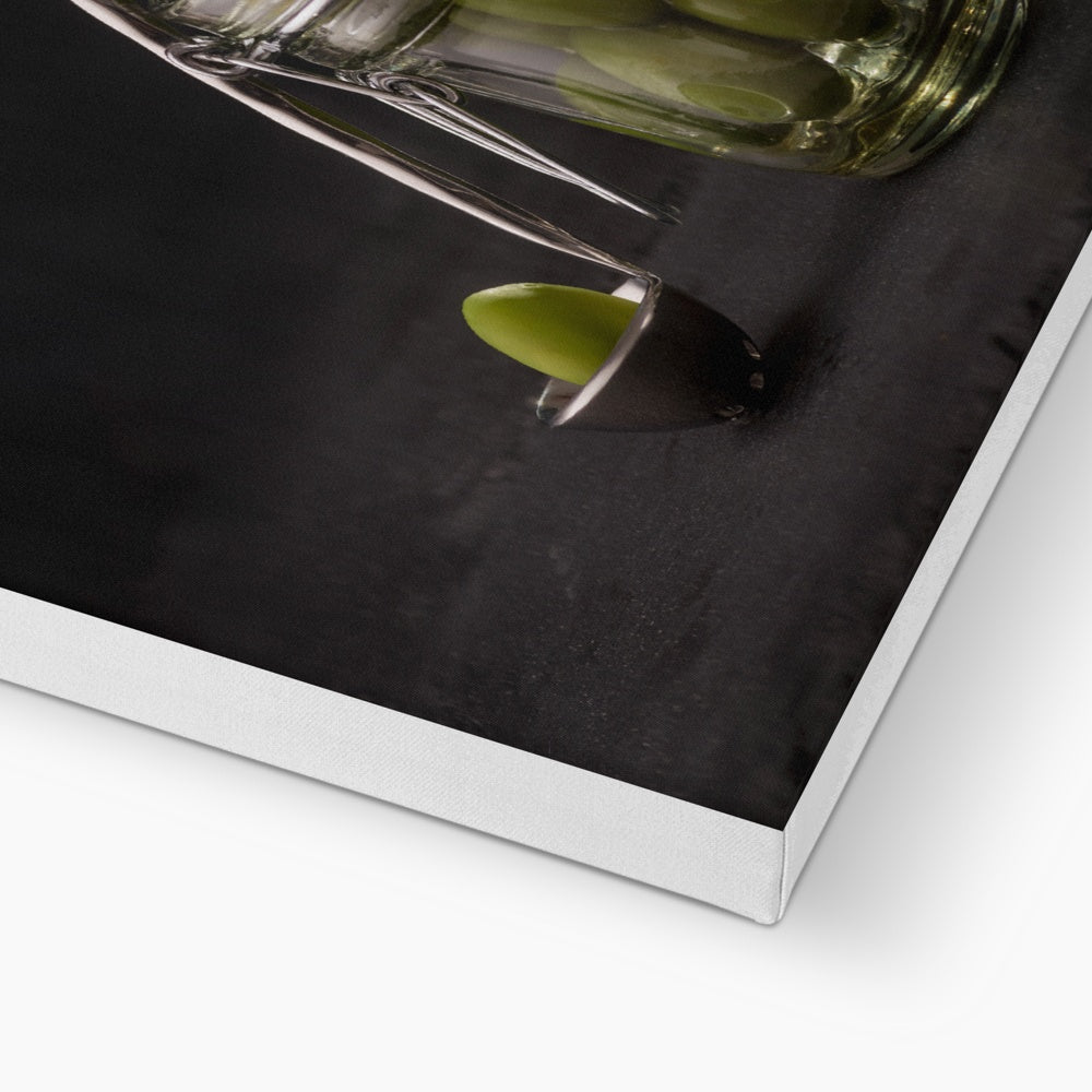 Jar of green olives with single olive on spoon against grey slate background. Canvas