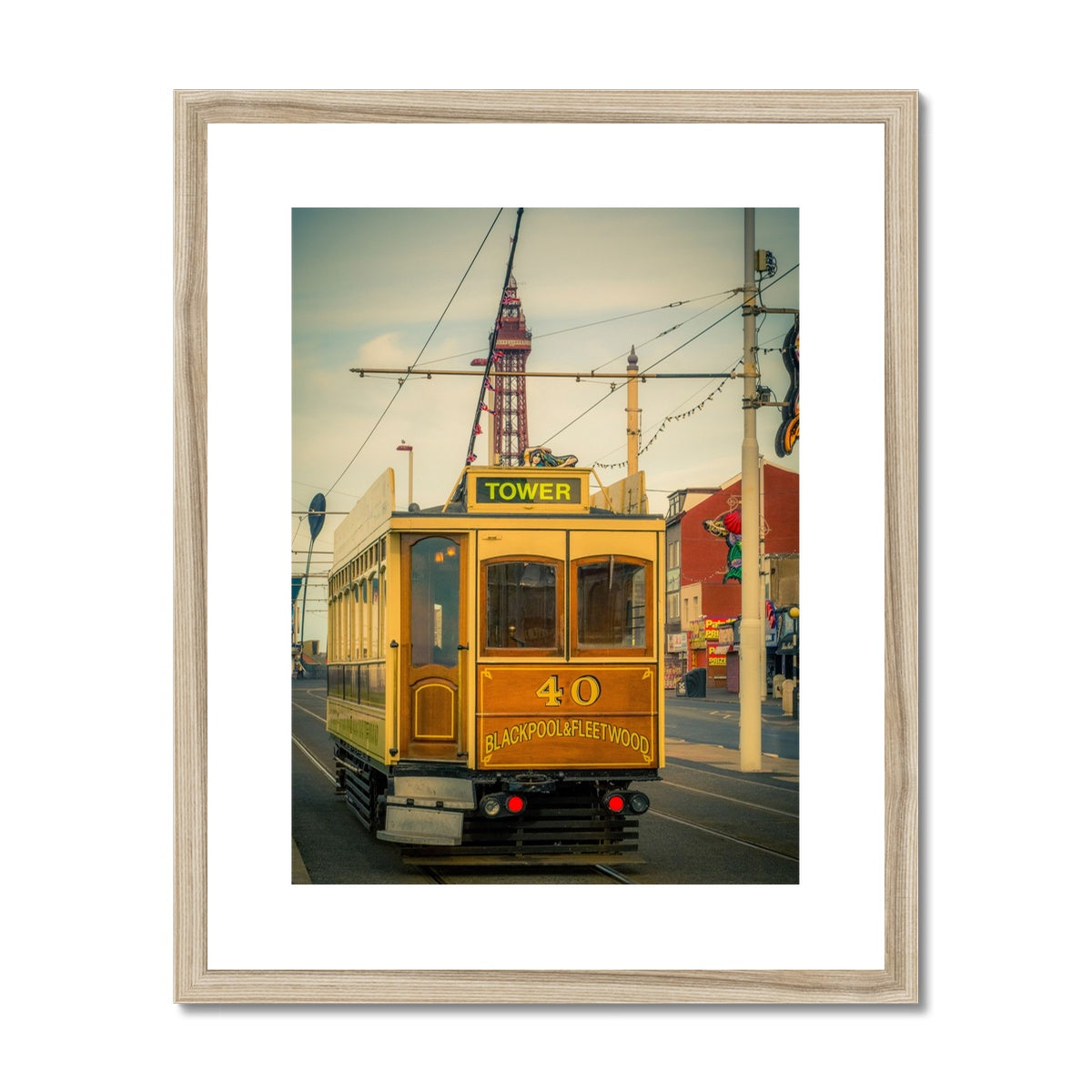 Traditional tram running along seafront promenade with Blackpool Tower in background - Blackpool,UK. Framed & Mounted Print