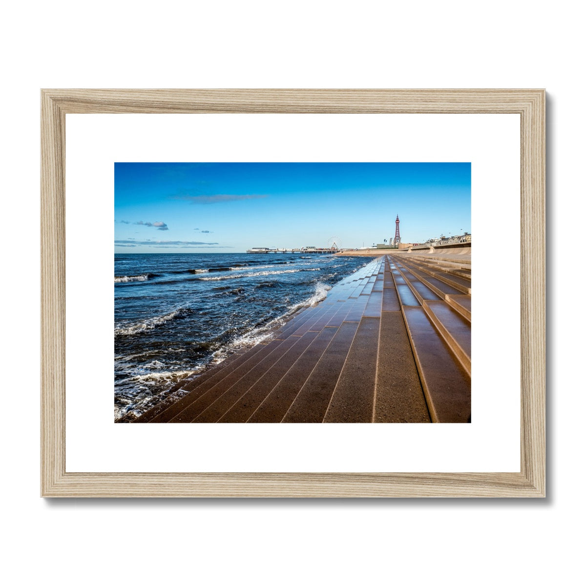 Blackpool's stone stepped sea defences with Blackpool Tower and Central Pier in the distance, Blackpool, UK. Framed & Mounted Print