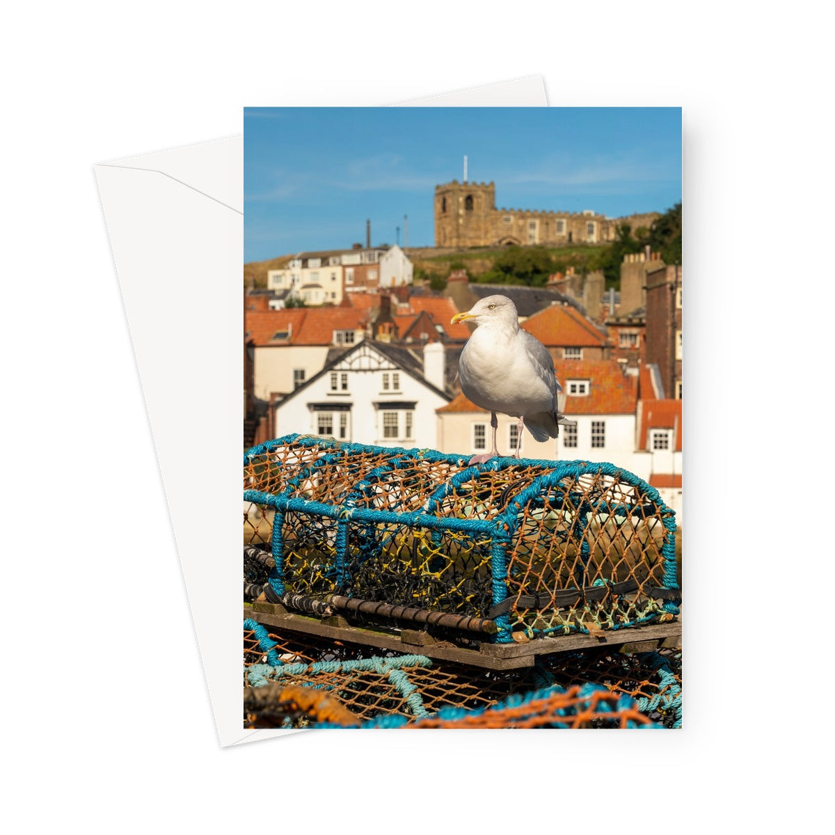 Seagull standing on a lobster trap on the quayside of Whitby harbour with St Mary's church in the distance. Whitby, UK. Greeting Card