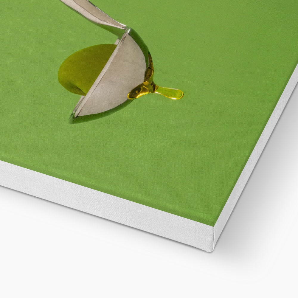 Single green olive on spoon with oil dripping. Canvas