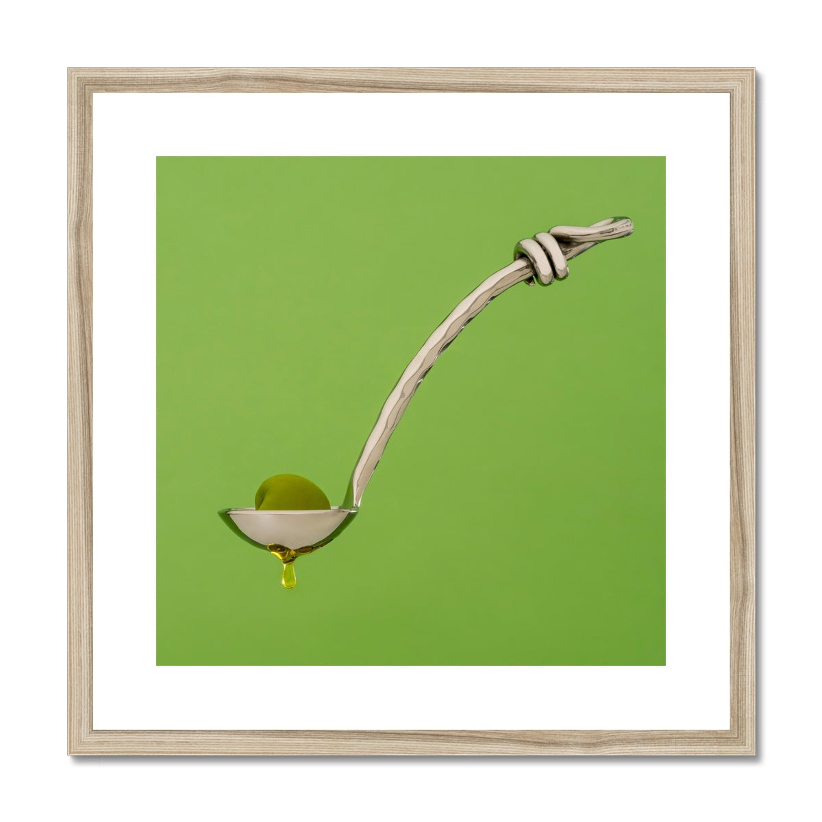 Single green olive on spoon with oil dripping. Framed & Mounted Print